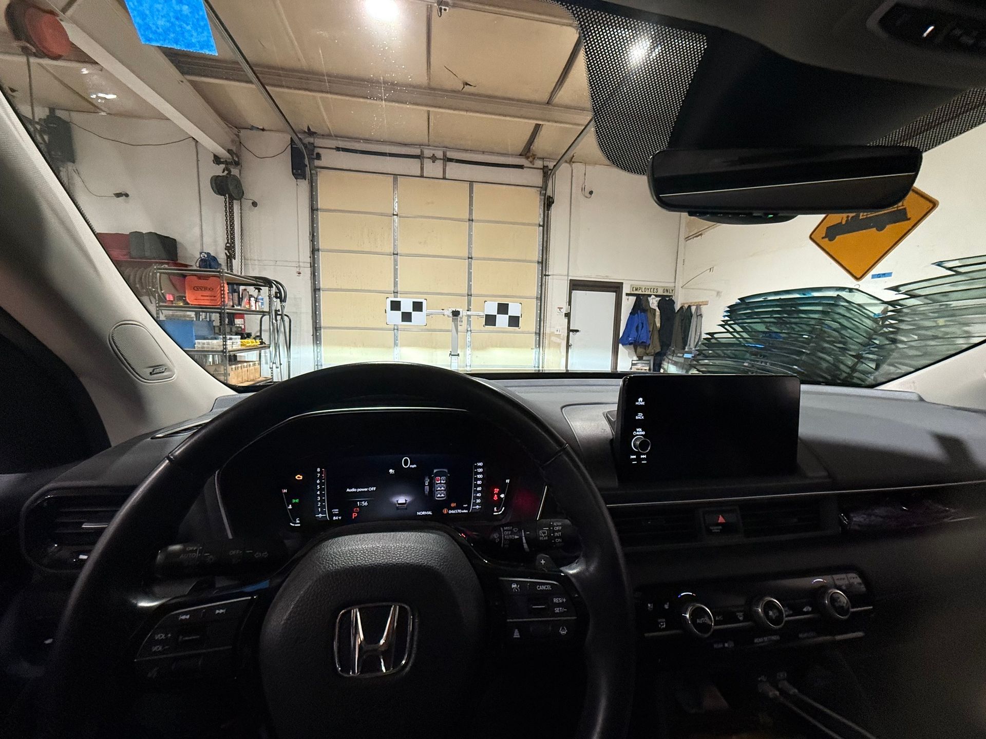 Interior view of a car looking at a garage door; steering wheel and dashboard in focus.