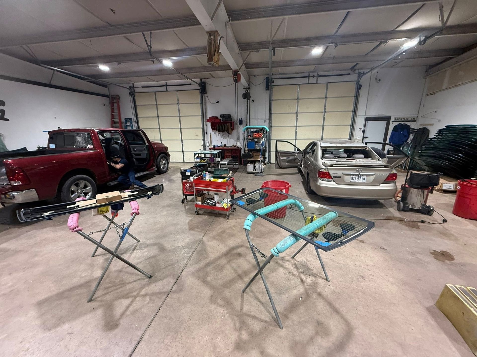 Auto body shop with a red pickup, a gold car, and tools.
