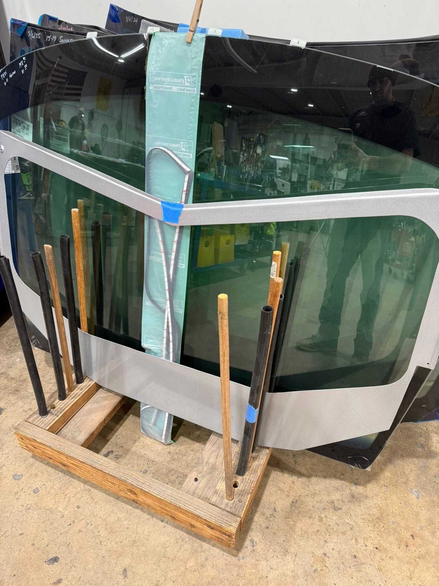 Glass panels on a wooden rack, some wrapped in protective material. Industrial setting.