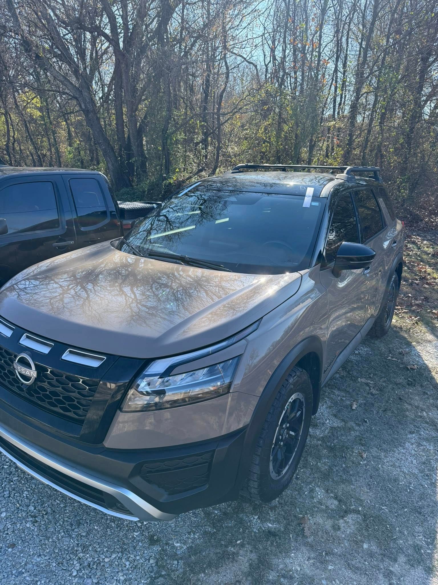 Gray Nissan Pathfinder SUV with black accents and roof rack, parked outdoors.