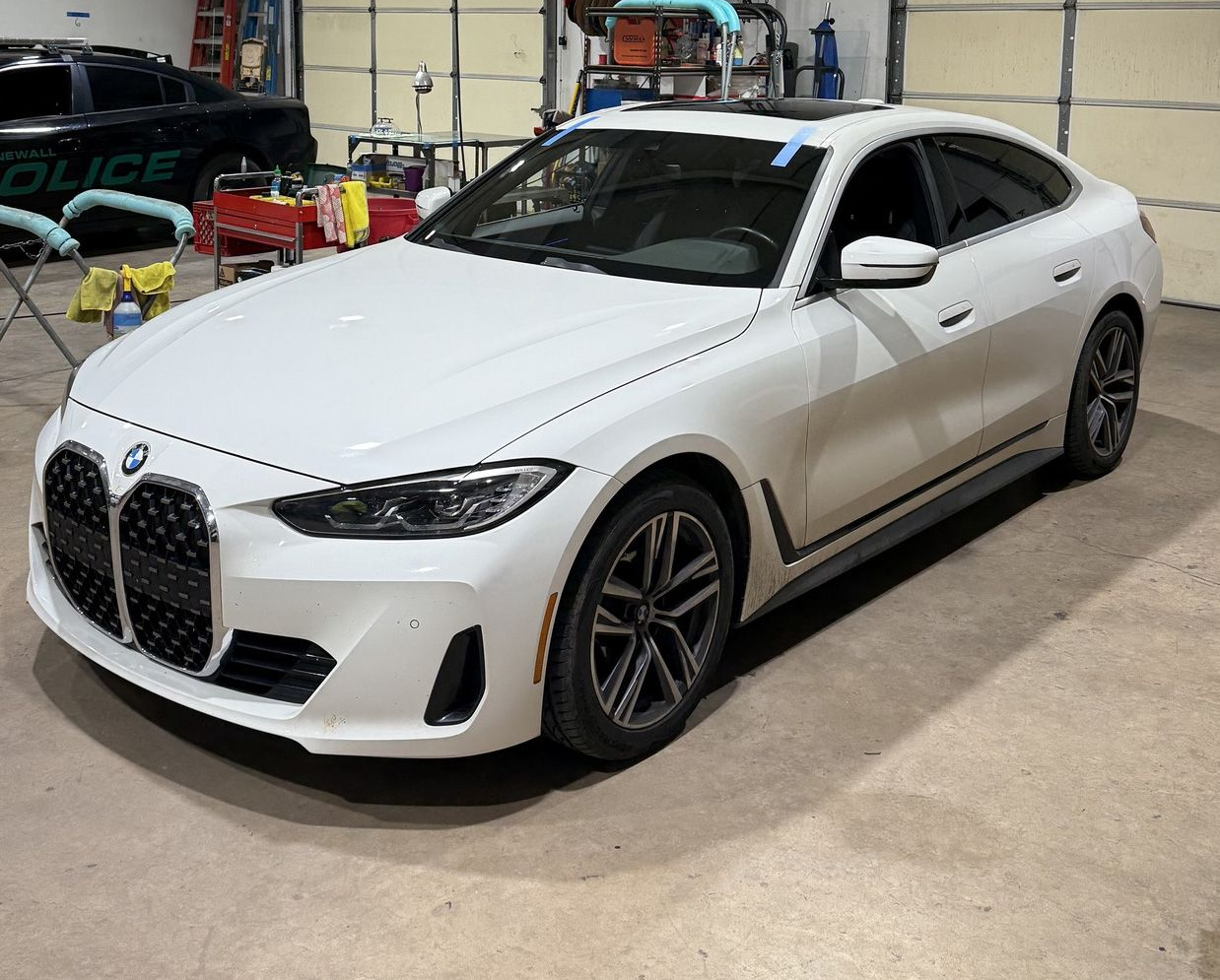 White BMW sedan parked inside a garage, possibly undergoing service.