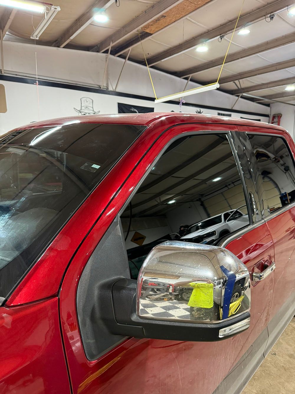 Red SUV in a garage, close-up of side mirror and tinted windows.