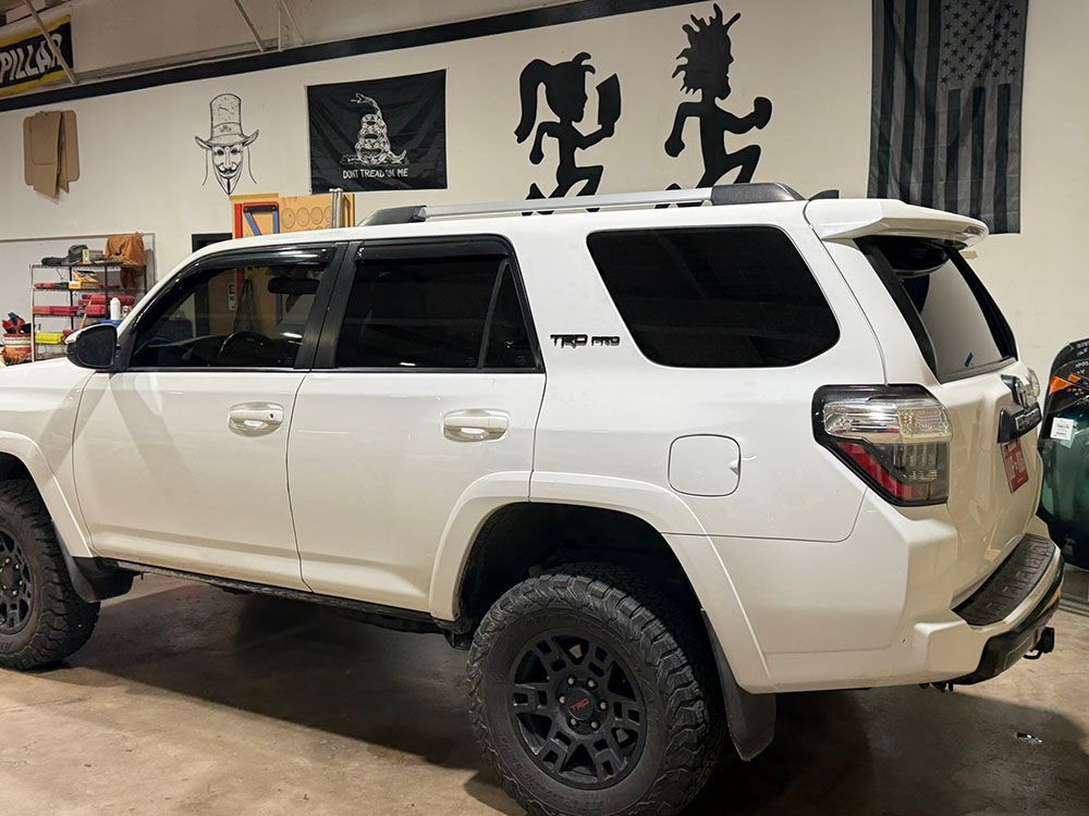 White SUV with off-road tires parked inside a garage, side view.