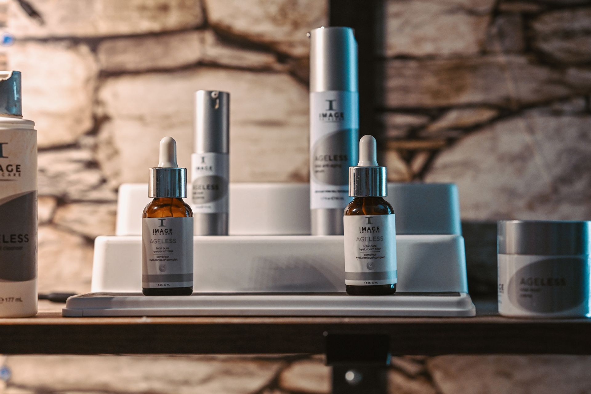 Various Image Skincare products displayed on a shelf against a stone wall backdrop.