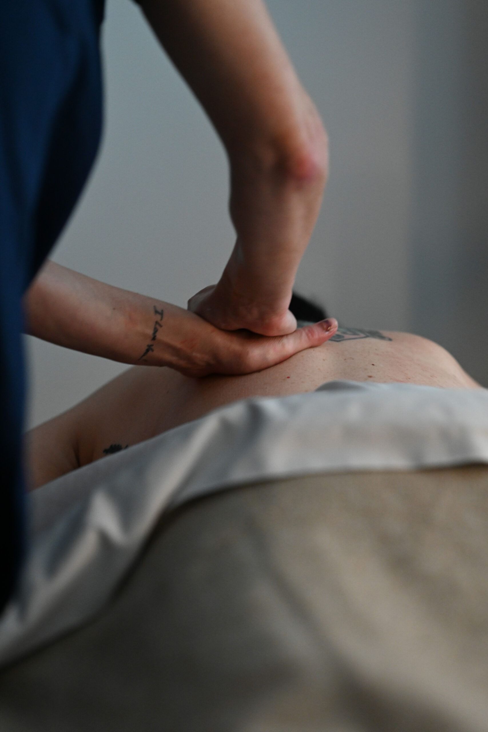 Person receiving massage on their back with stone, light setting.