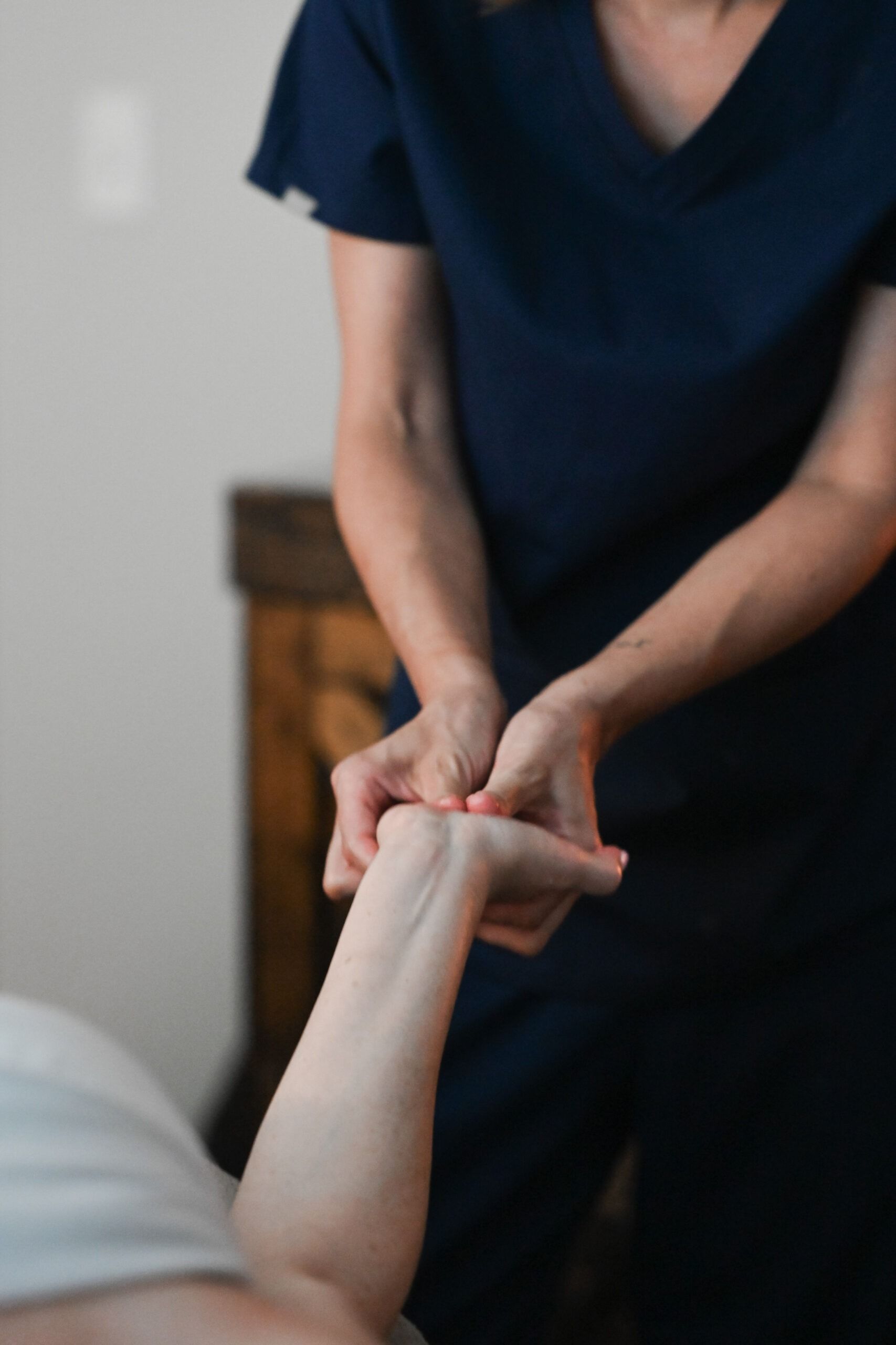 Person in blue scrubs giving a wrist massage.