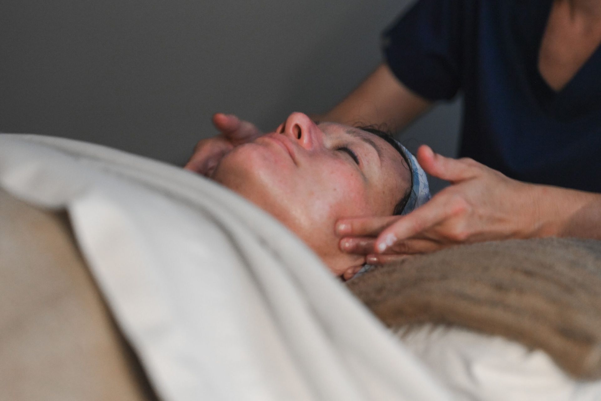 Woman receiving a facial massage in a spa. Aesthetican's hands on her face.