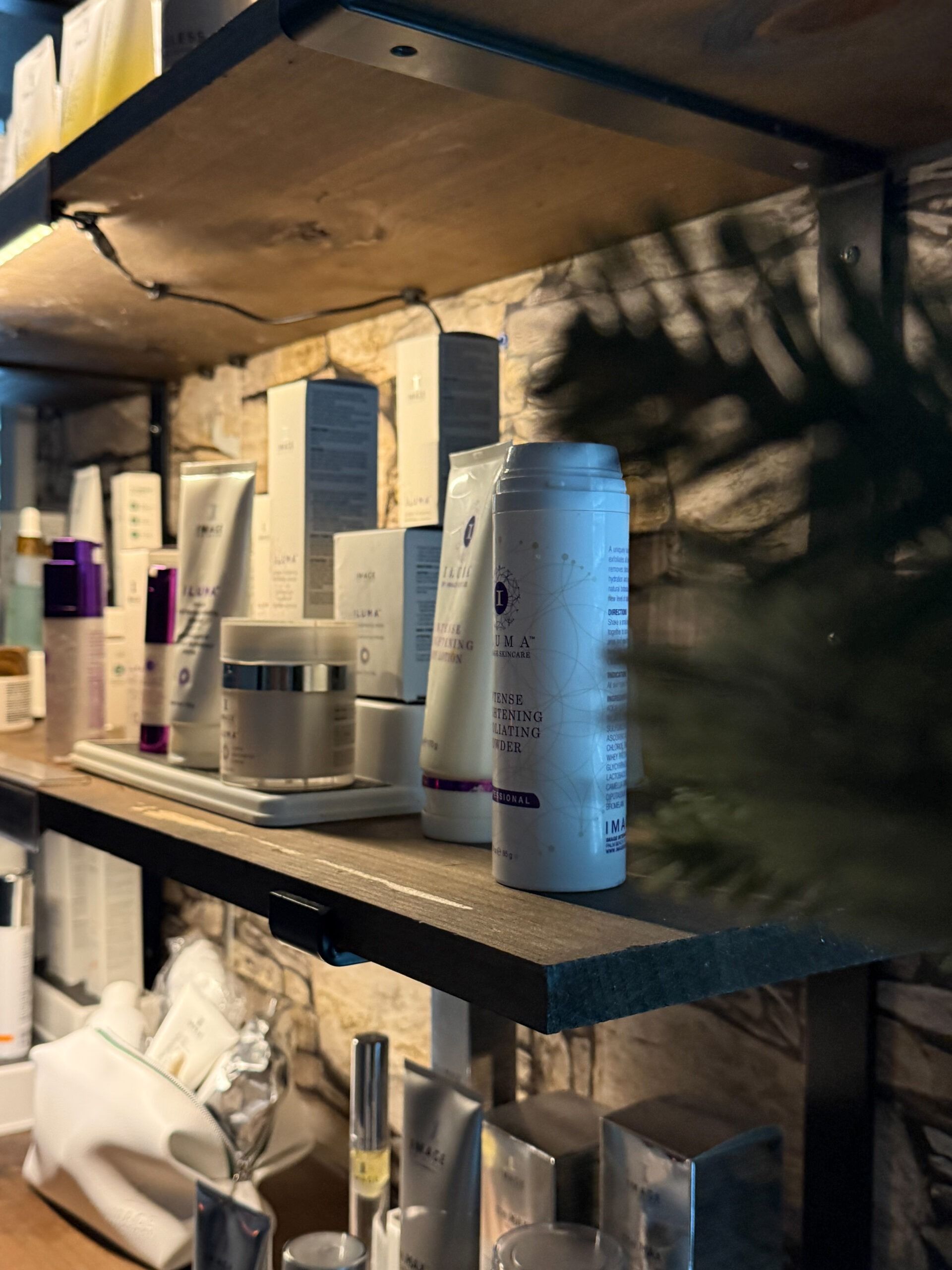 Shelves holding various skincare products in white and silver packaging, with a shadow of palm leaves.