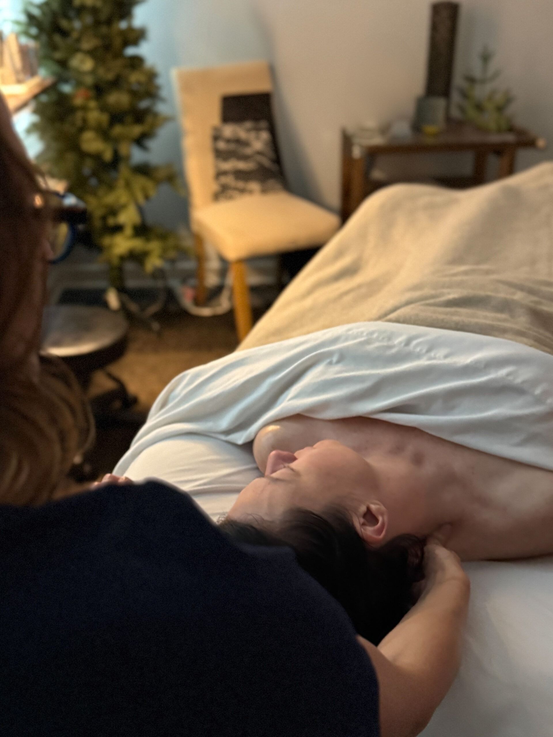 Person receiving a massage in a dimly lit room.