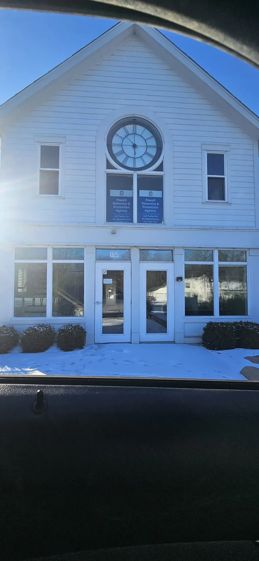 White building with a large clock, windows, and snow on the ground.