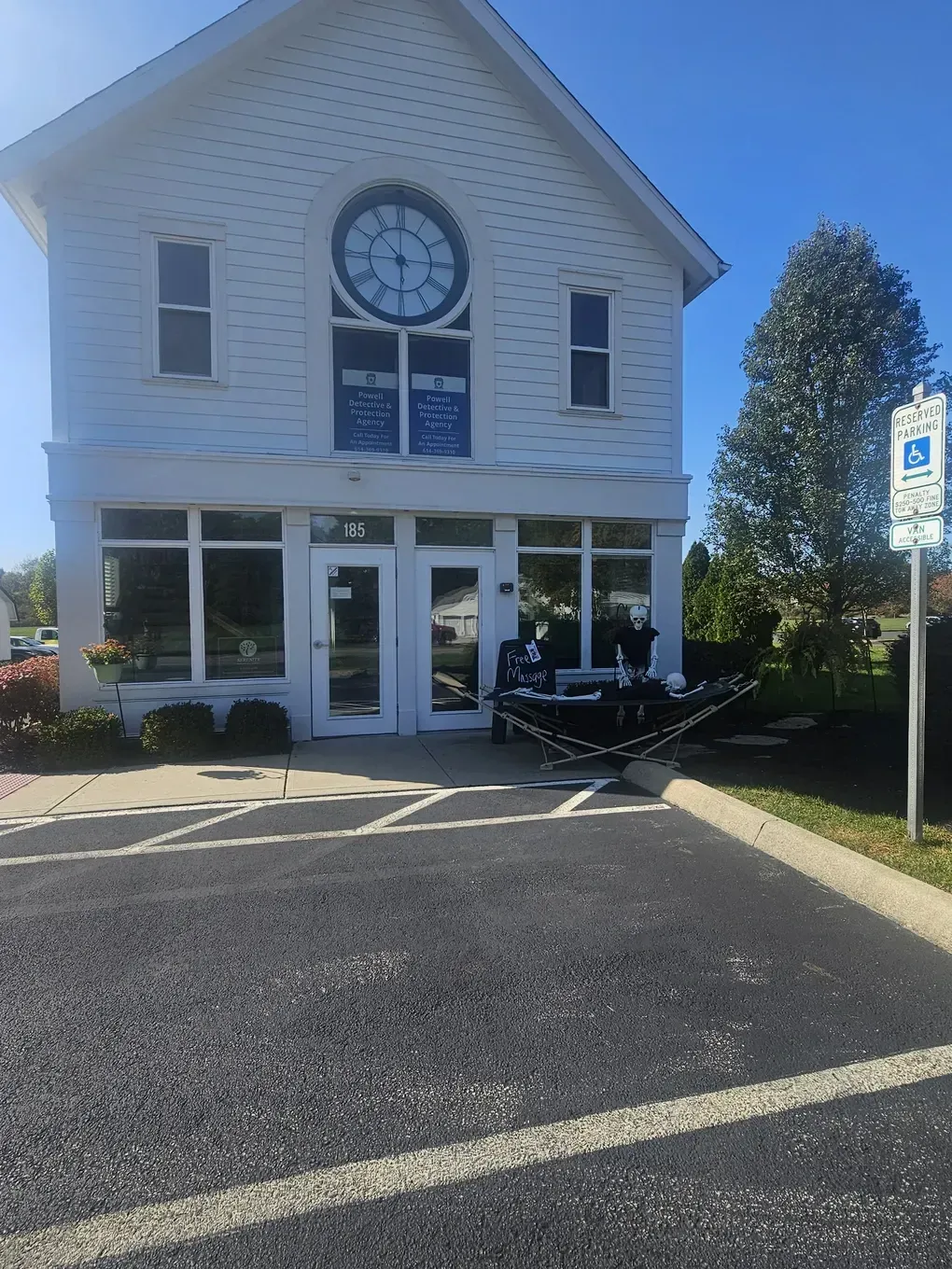 White building with clock and windows. Handicapped parking sign visible.