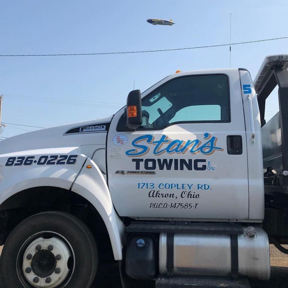 White Stan's Towing truck parked outdoors with company logo and contact number on the door