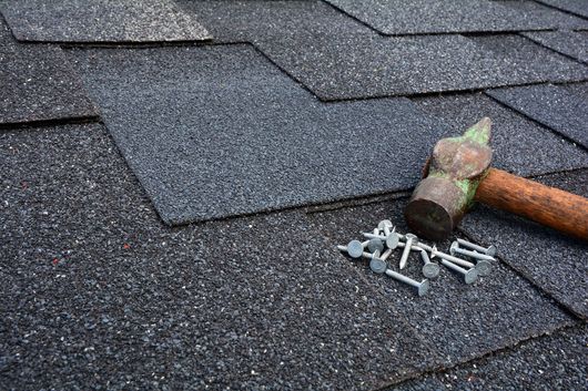 A hammer and nails are laying on a roof.