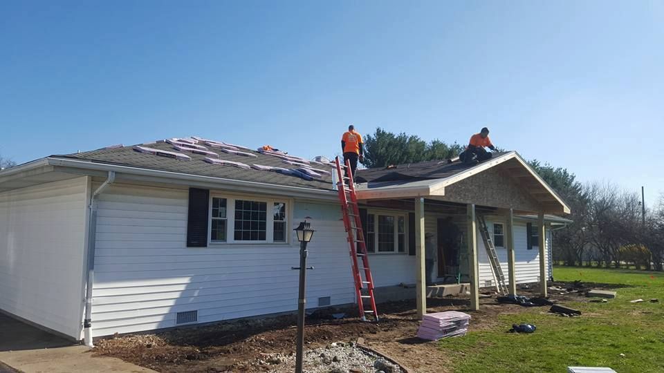Two men are working on the roof of a house.