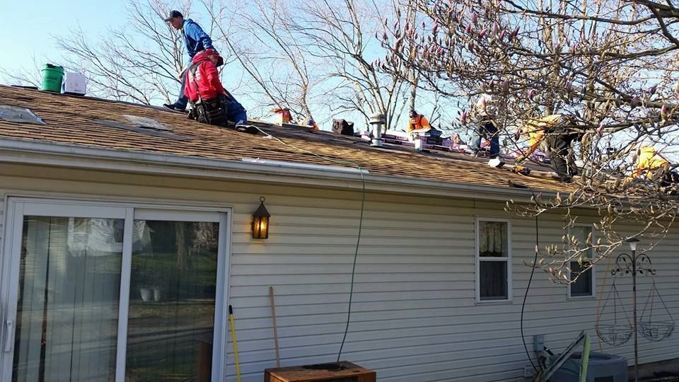 A group of people are working on the roof of a house.
