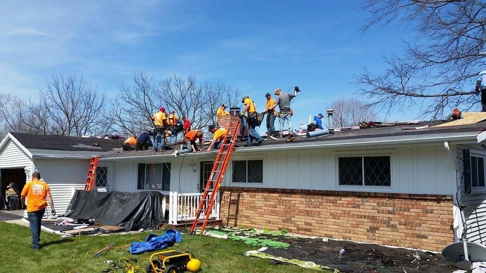 A group of people are working on the roof of a house.