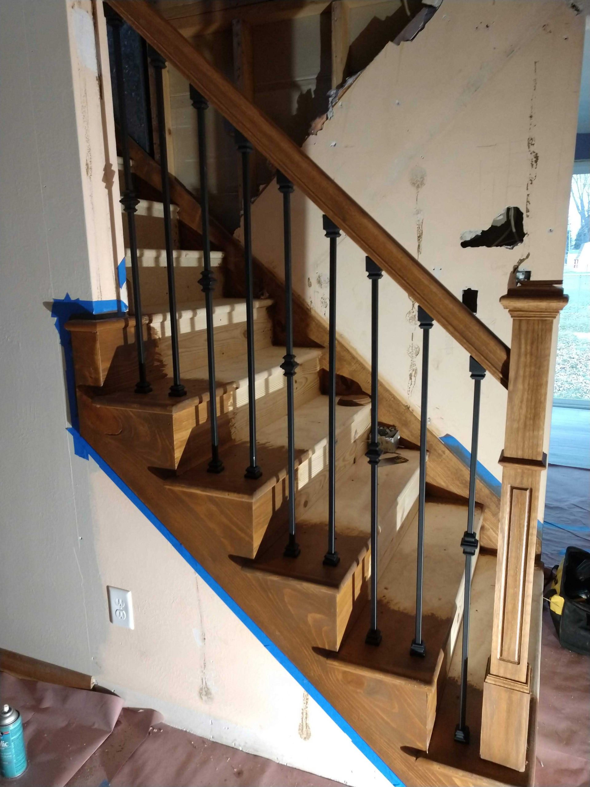 Wooden staircase with dark metal spindles and a wooden handrail. Construction in progress.