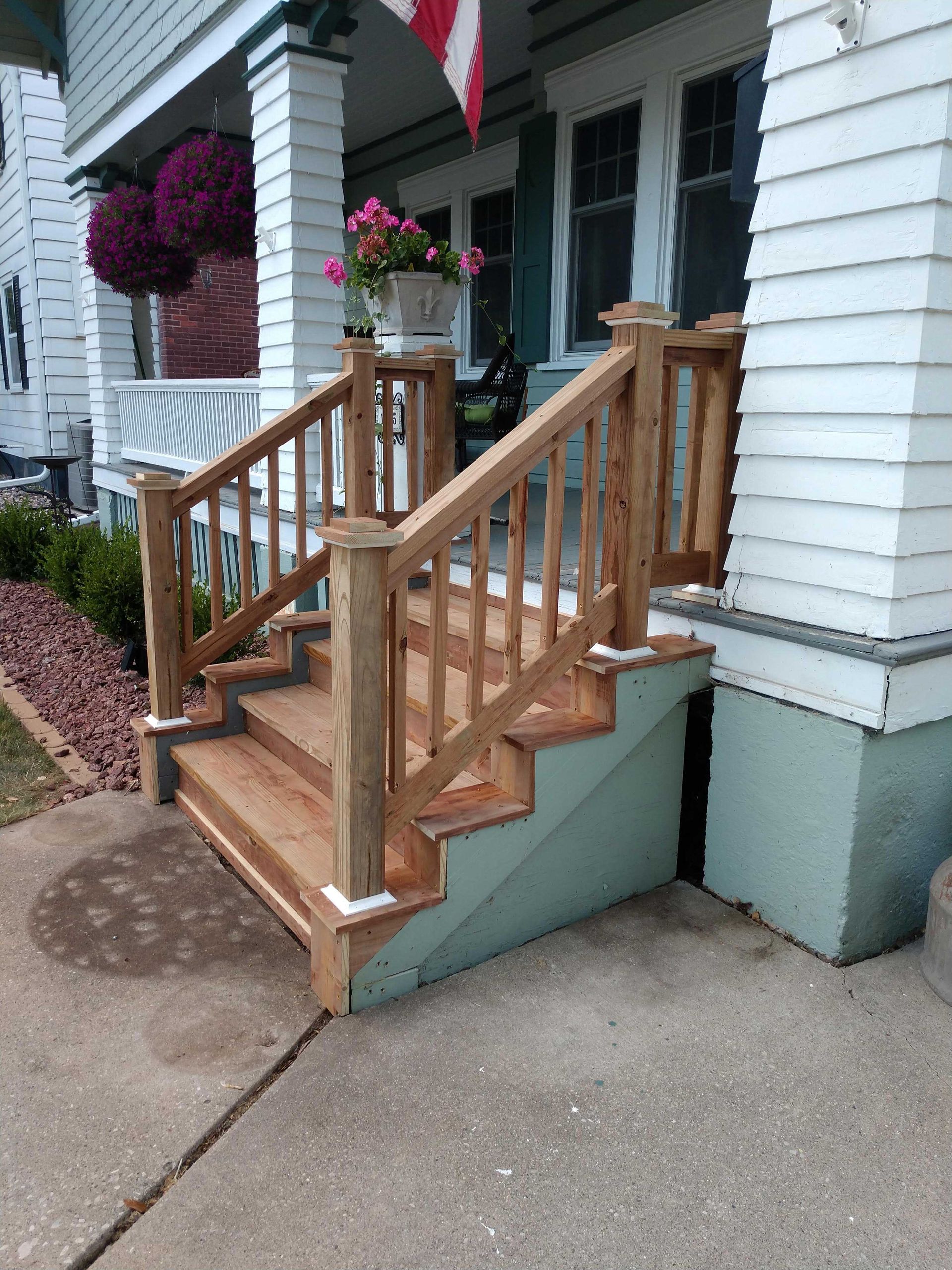 Wooden front porch steps with railing; house exterior.