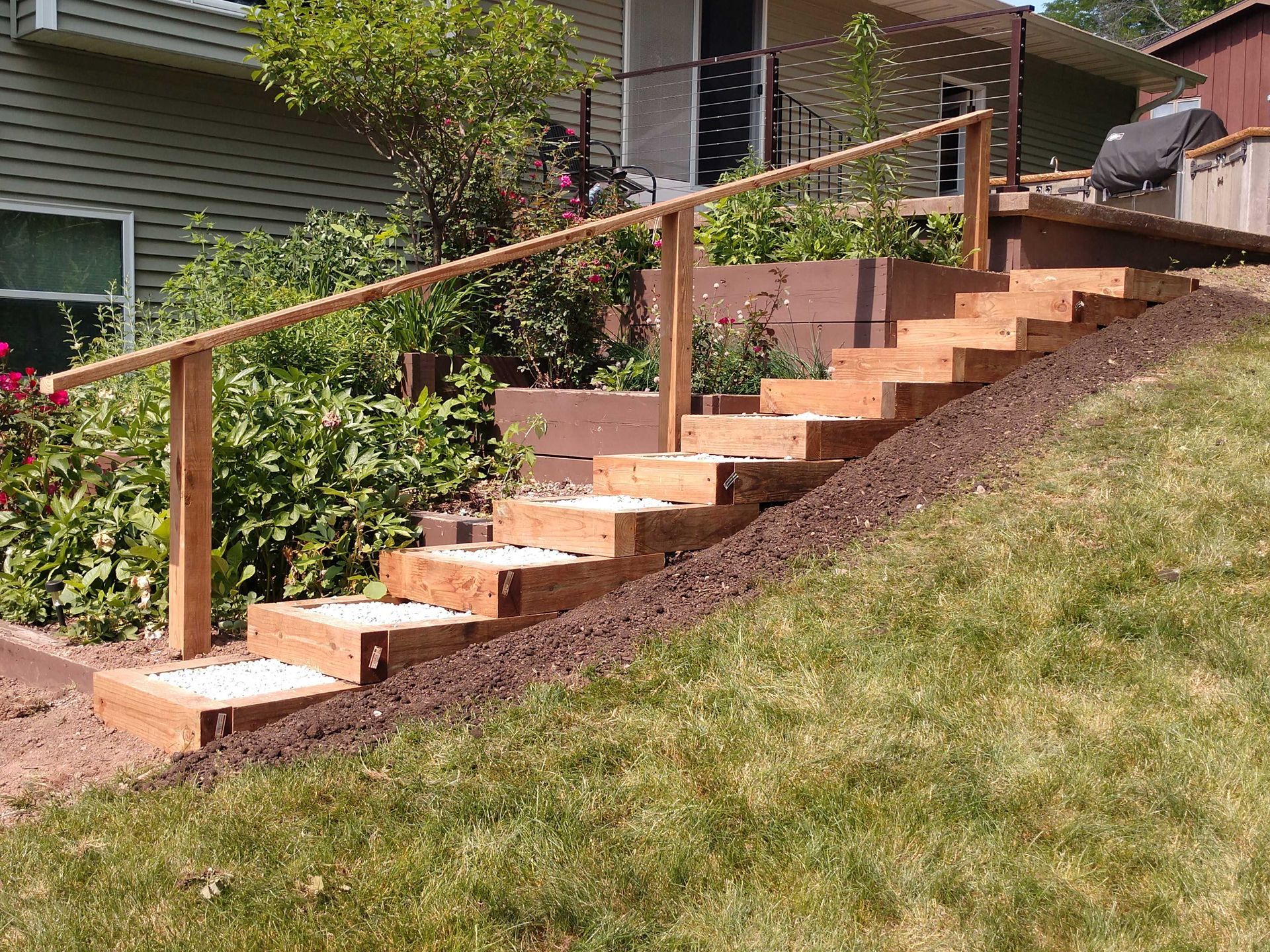 Wooden steps with handrail leading up a grassy hill.