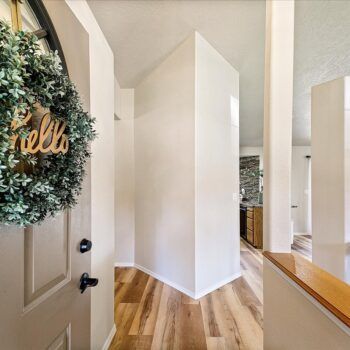 An entryway featuring wood-look floors, a white interior wall, and a grey front door decorated with a 