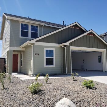 Two-story residential house with light green horizontal siding, olive green vertical siding, and an open two-car garage.