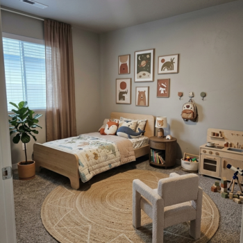 A cozy, earth-toned children’s bedroom with a twin bed, wooden play kitchen, round jute rug, and framed animal wall art.
