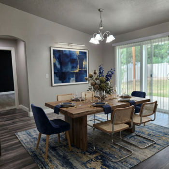 A dining room with a wooden table, blue velvet chairs, cane-back chairs, and a blue abstract painting on a grey wall.