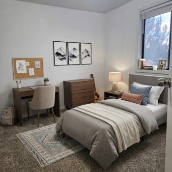 A neutrally toned bedroom with a twin bed, a wooden desk with a beige chair, a dresser, and minimalist mountain art.