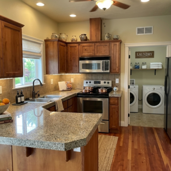Kitchen with wooden cabinets, granite countertops, and stainless appliances, opening into a laundry room with washer/dryer.