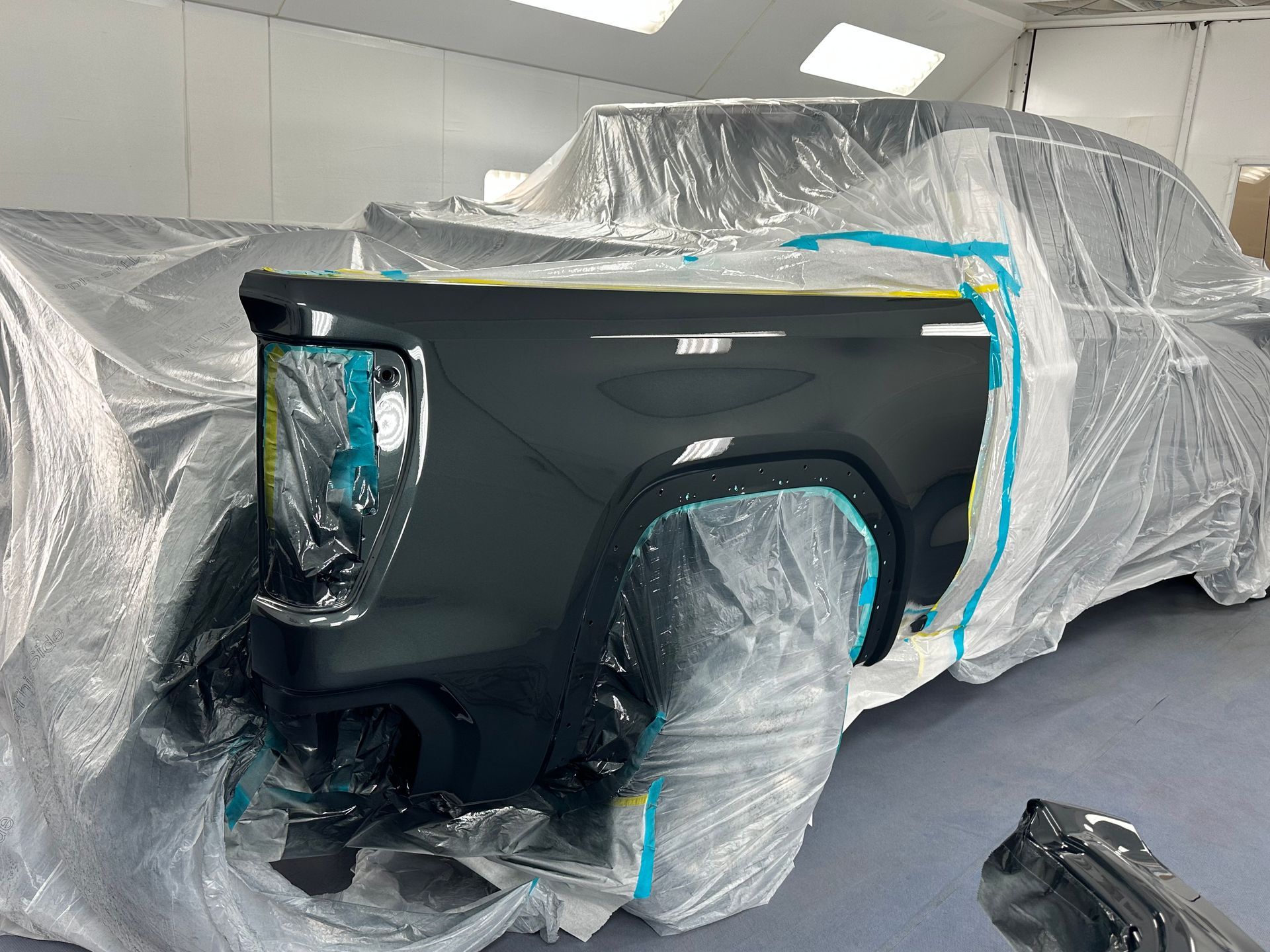 A black truck is being painted in a garage after.