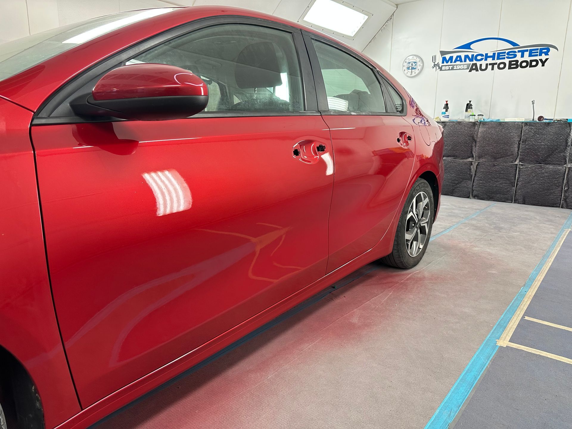 A red car is being painted in a paint booth after.