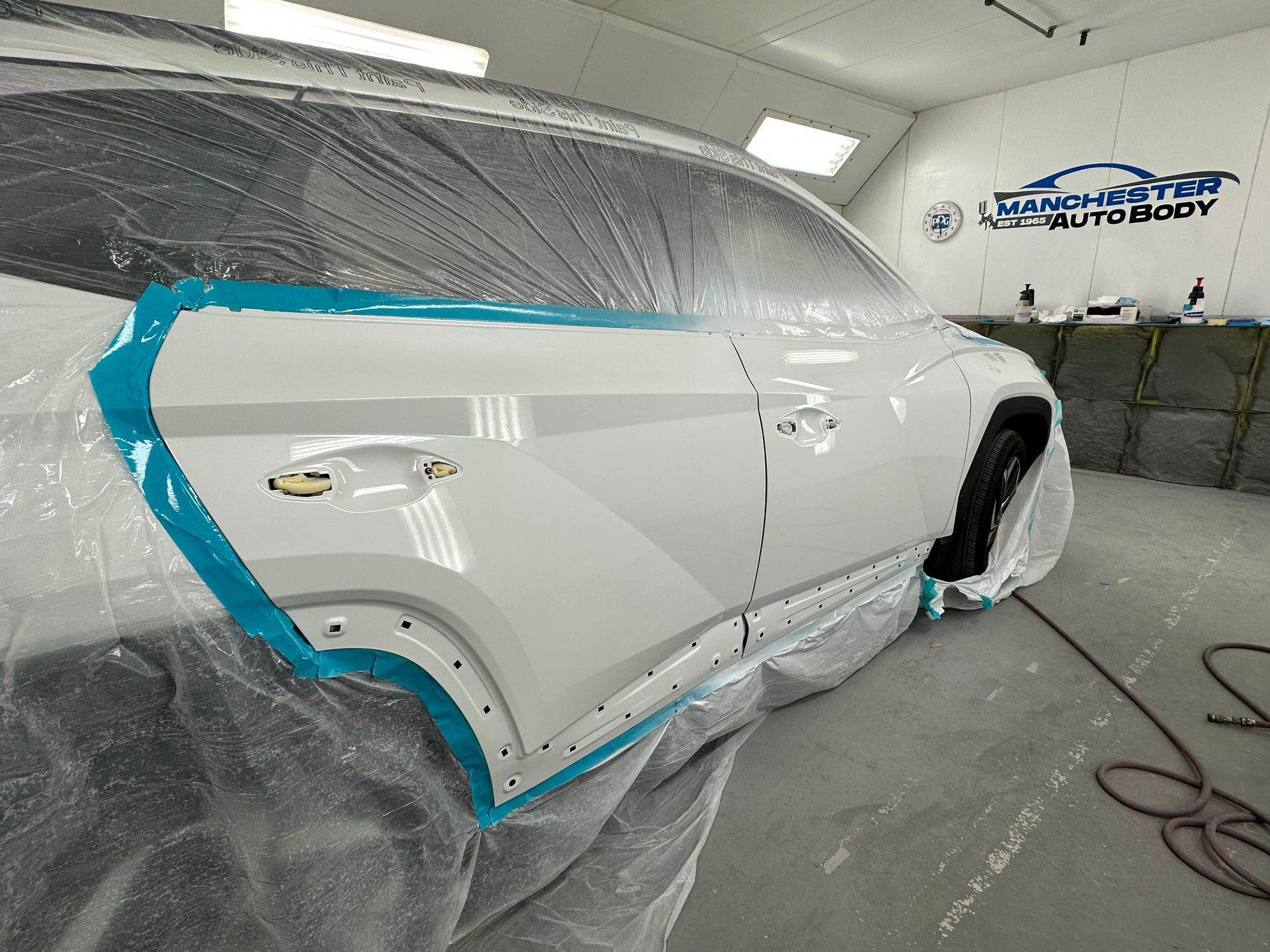 A white car is being painted in a paint booth after.