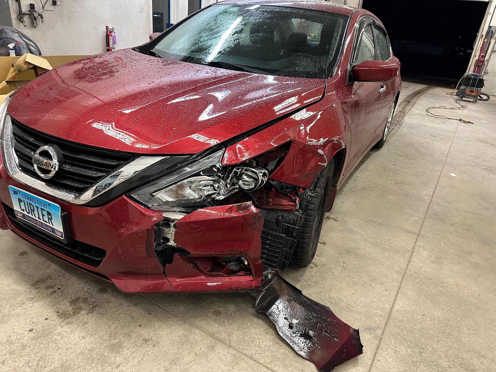 A red nissan altima is parked in a parking lot before