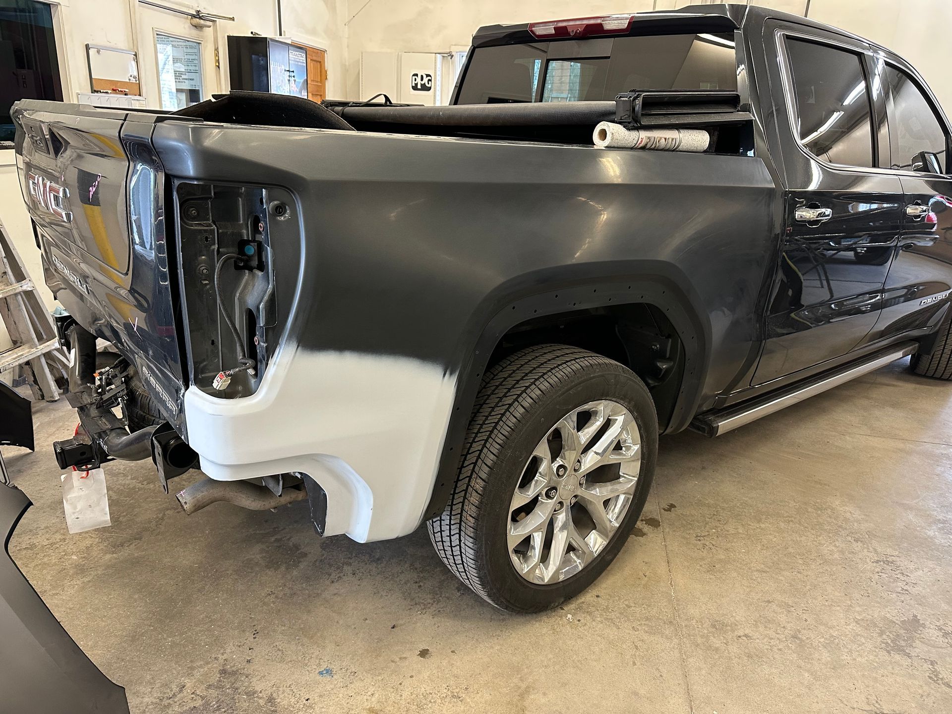 A black truck is being painted in a garage before.