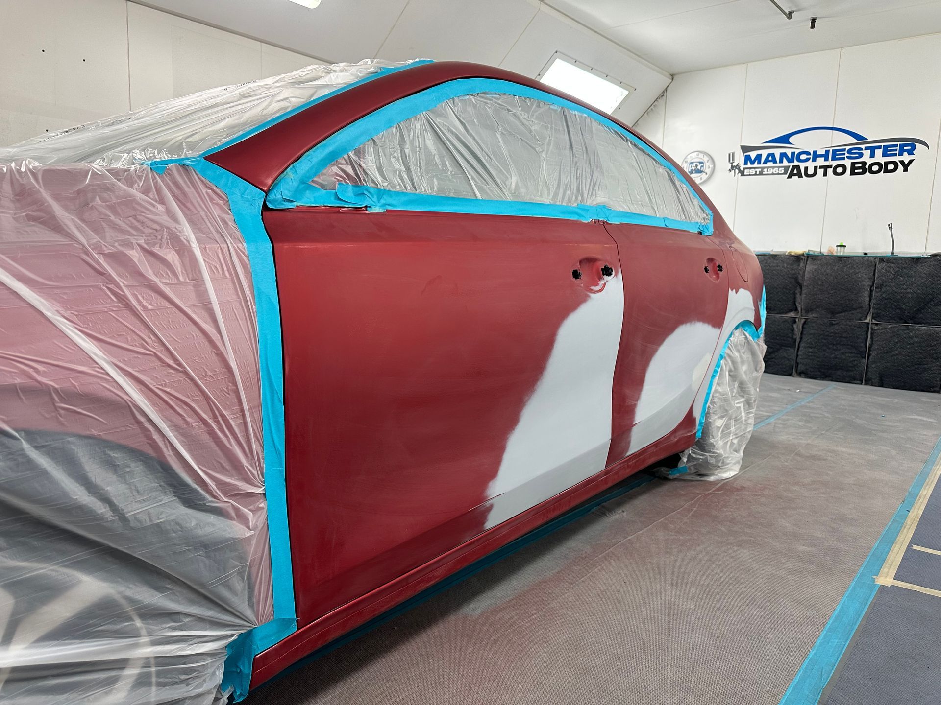 A red car is being painted in a paint booth before