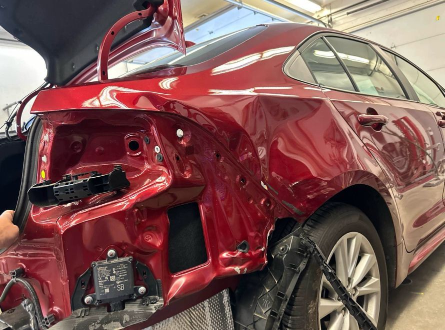 A red car is being repaired in a garage.