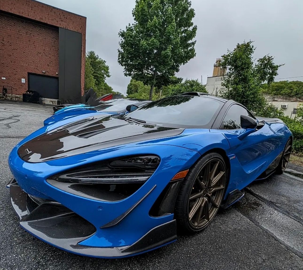 A blue sports car is parked on the side of the road in front of a building.