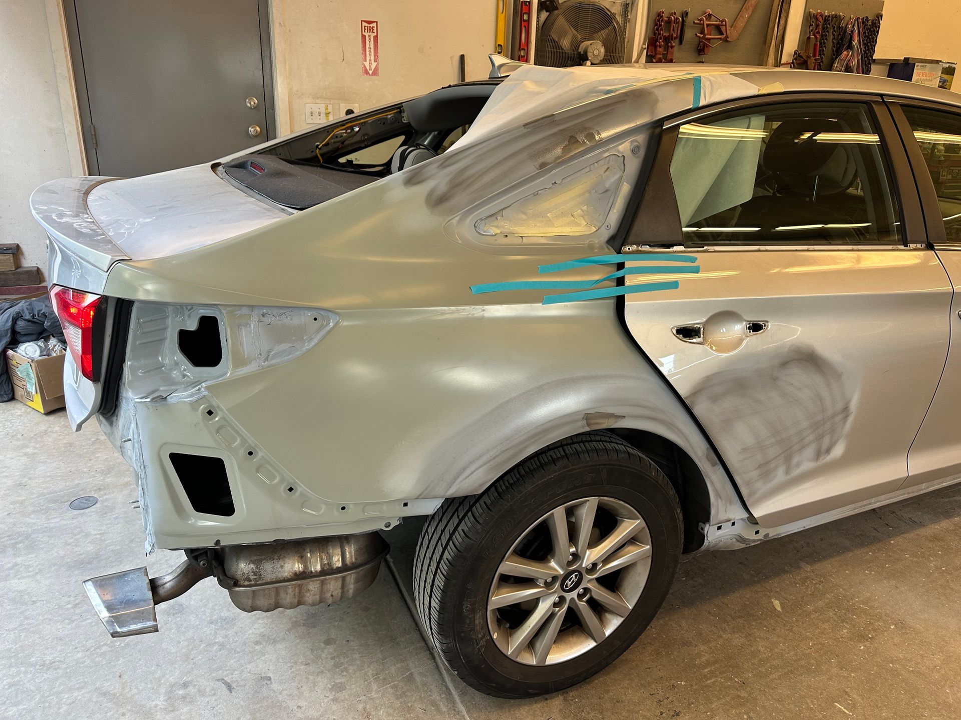 A silver car is being repaired in a garage.