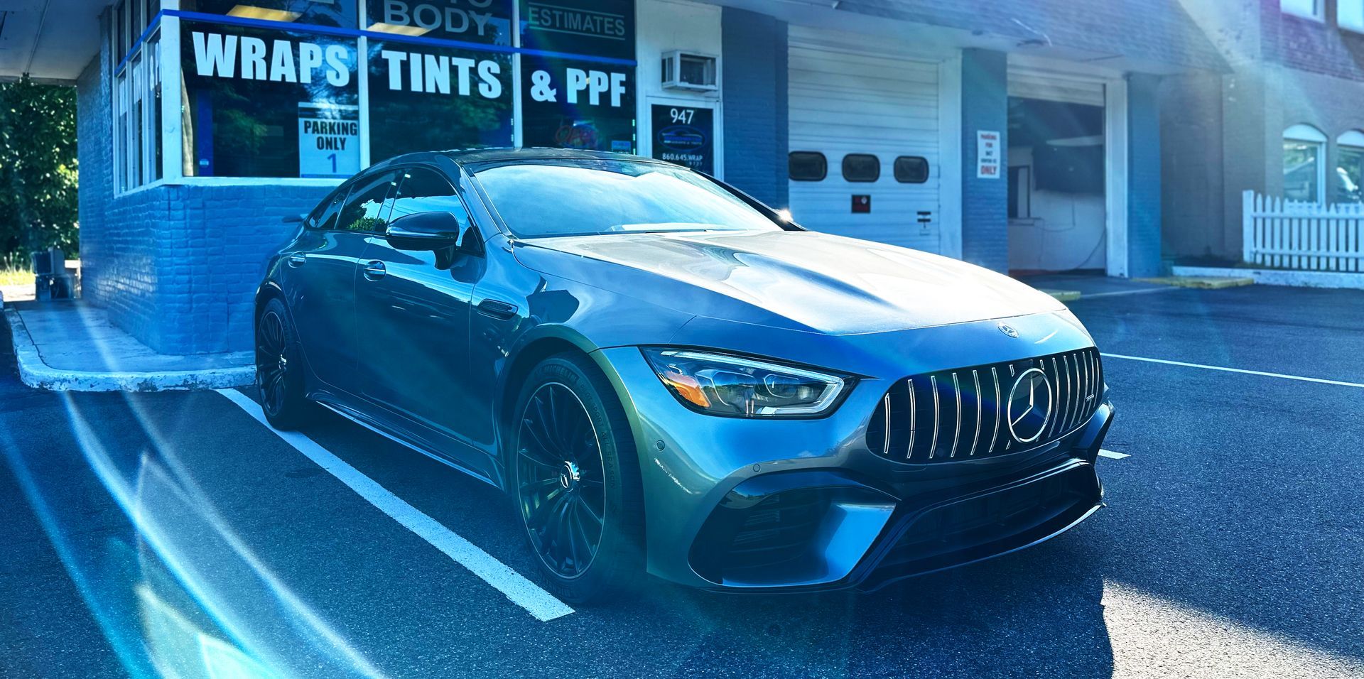 A blue car is parked in a parking lot in front of a building.