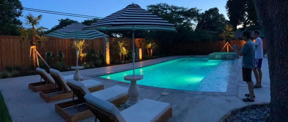 Pool with umbrellas, lounge chairs, and two people taking photos.