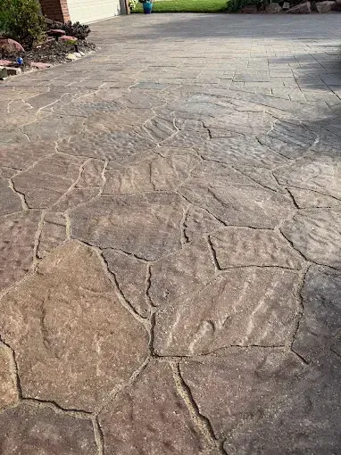 A ground-level view of a patio featuring dark, textured flagstone pavers with irregular shapes and dark grout lines.