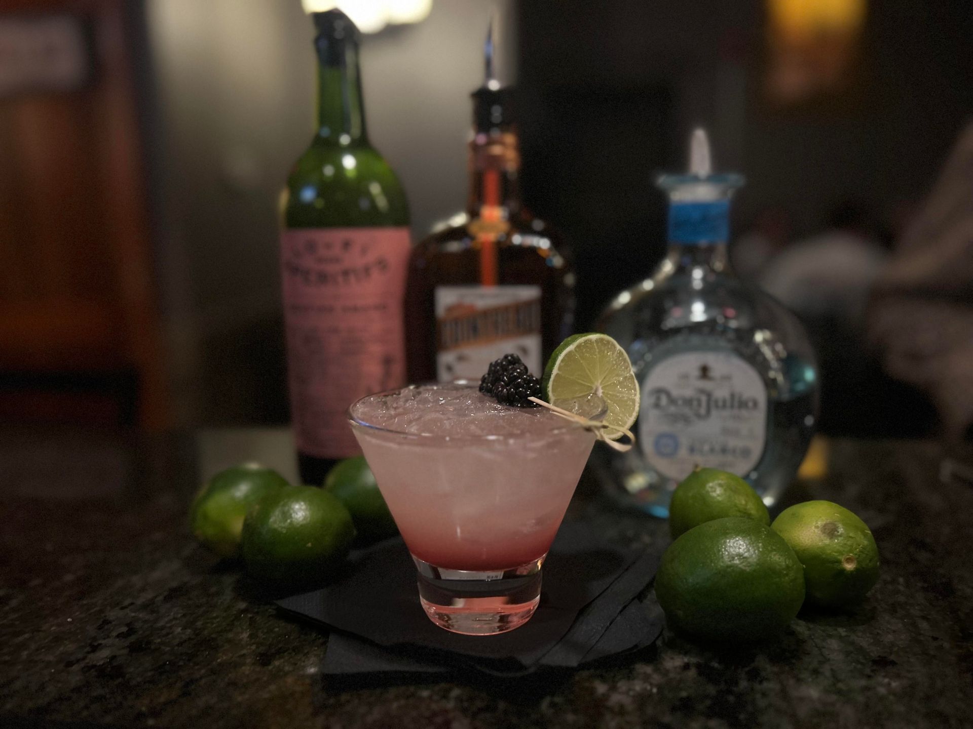 A margarita in a martini glass with a blackberry garnish