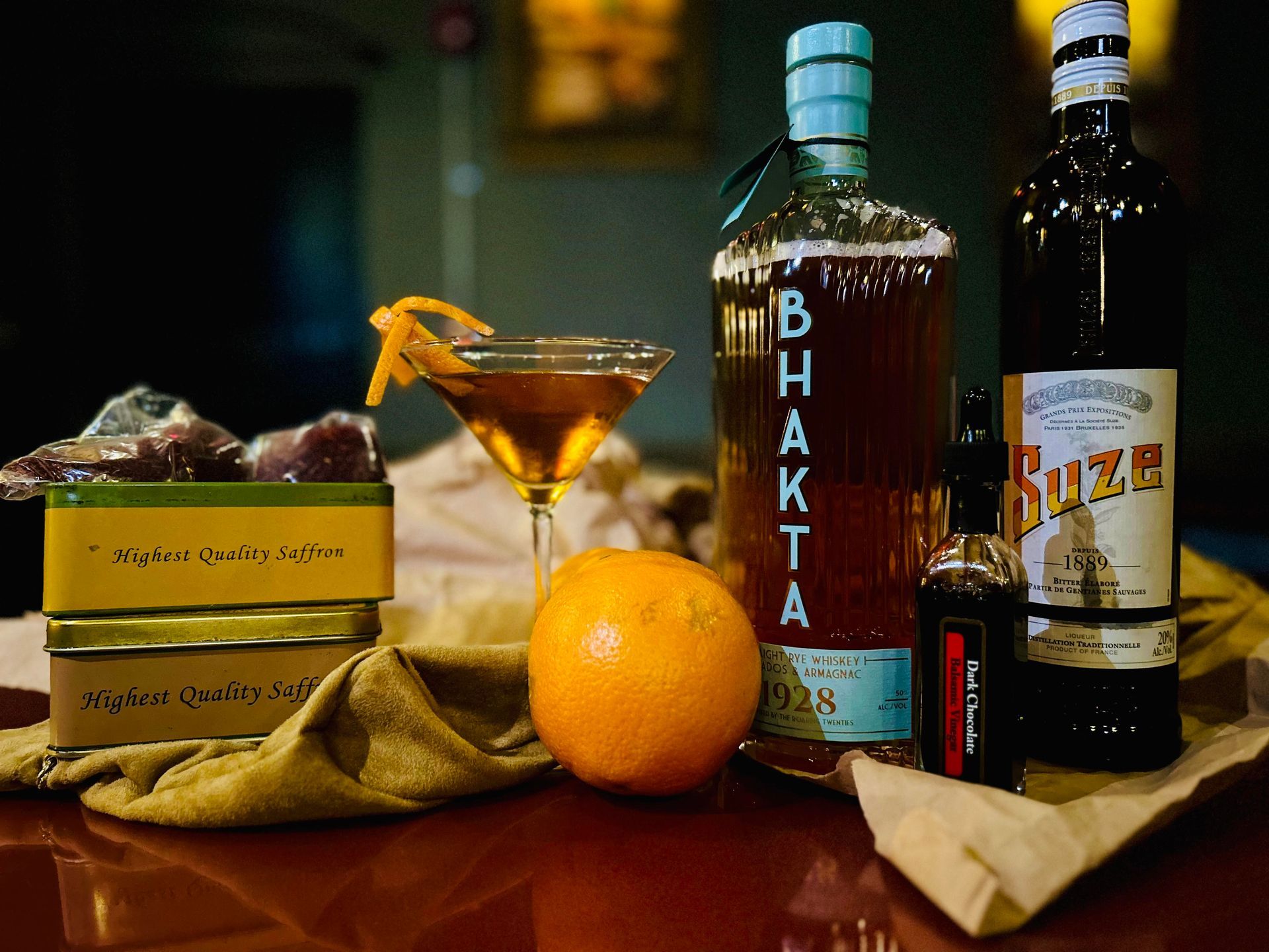 A bottle of bhakti is on a table next to a martini glass