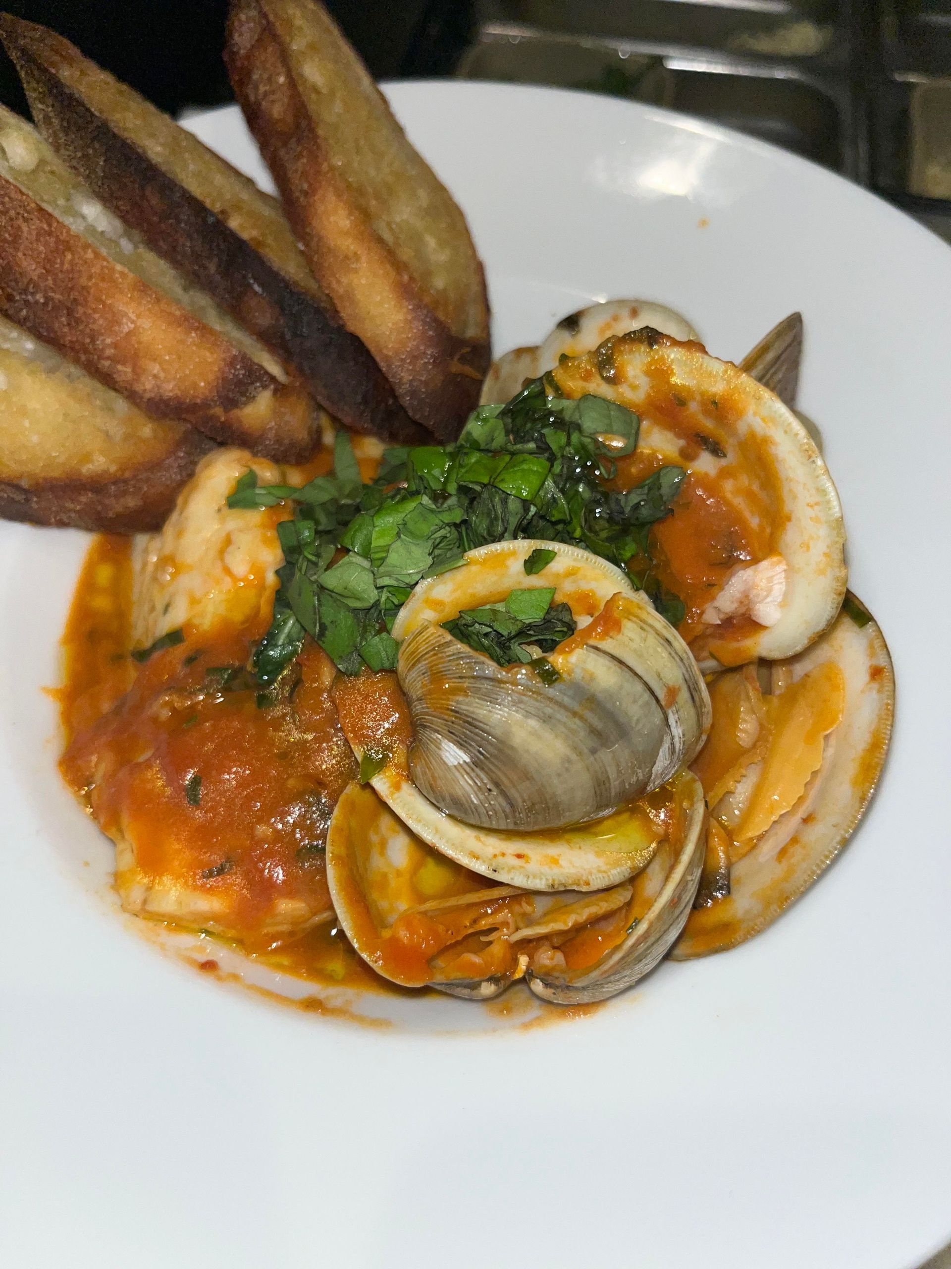 A close up of a plate of food with clams and bread on a table.