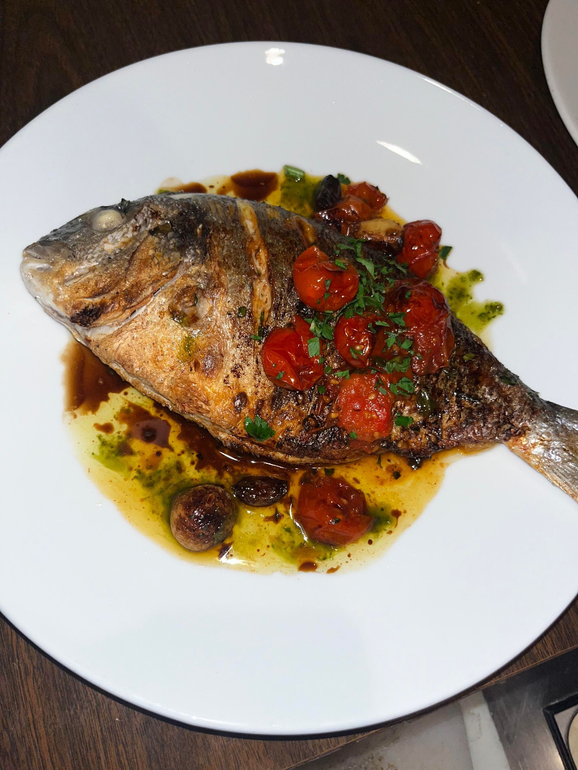 A white plate topped with a fish and tomatoes