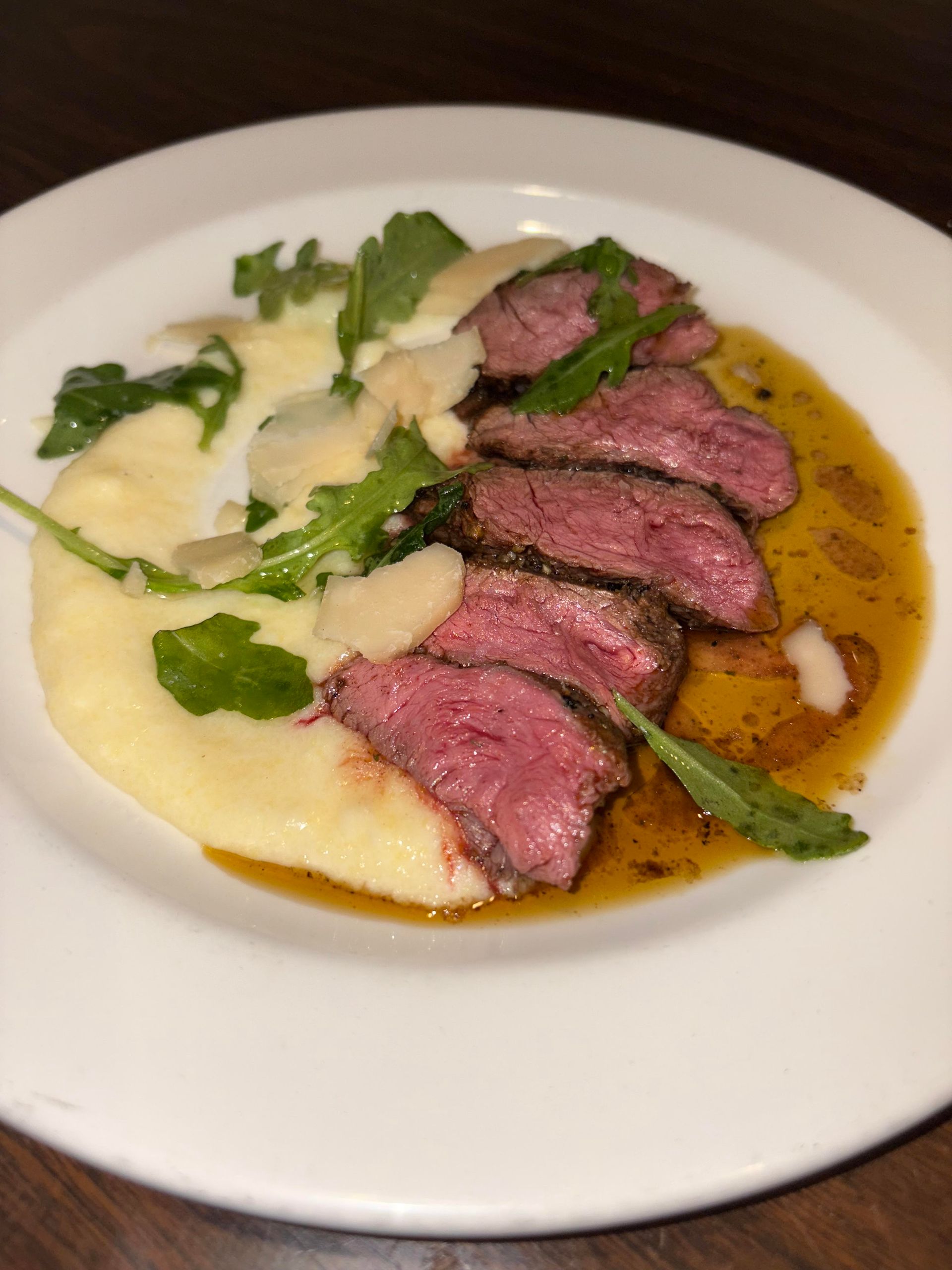 A white plate topped with meat and mashed potatoes