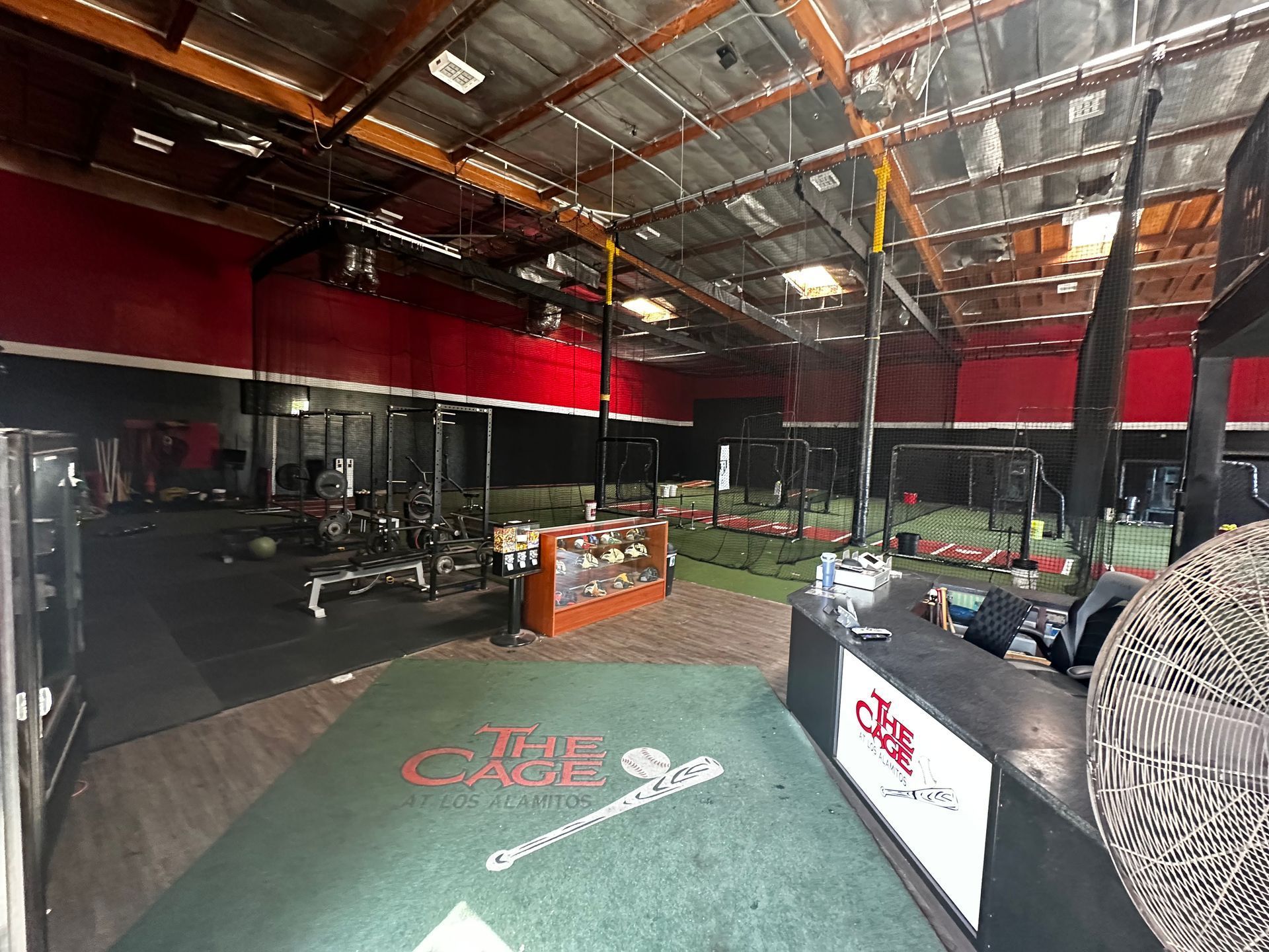 A large empty gym with a green floor and a red ceiling.