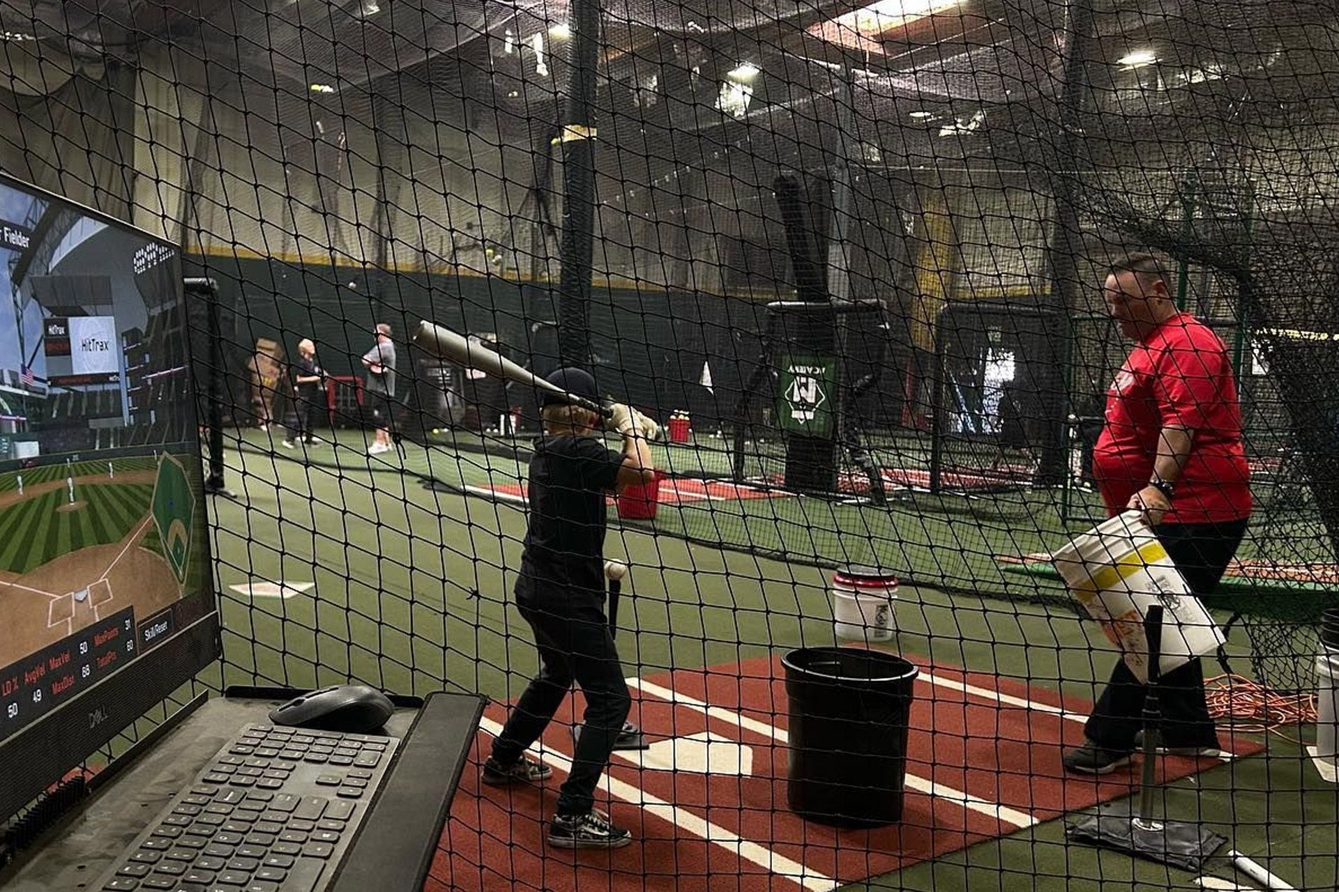 A young boy is swinging a baseball bat in a cage.