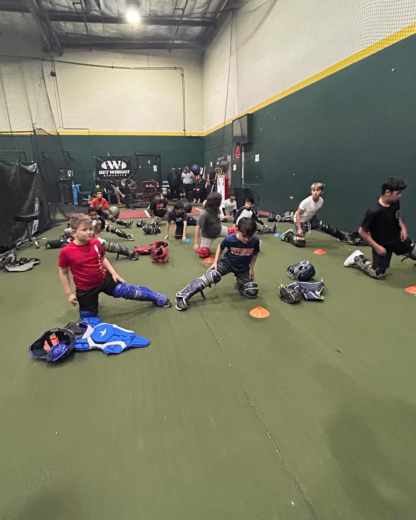 A group of people are doing stretching exercises in a gym.