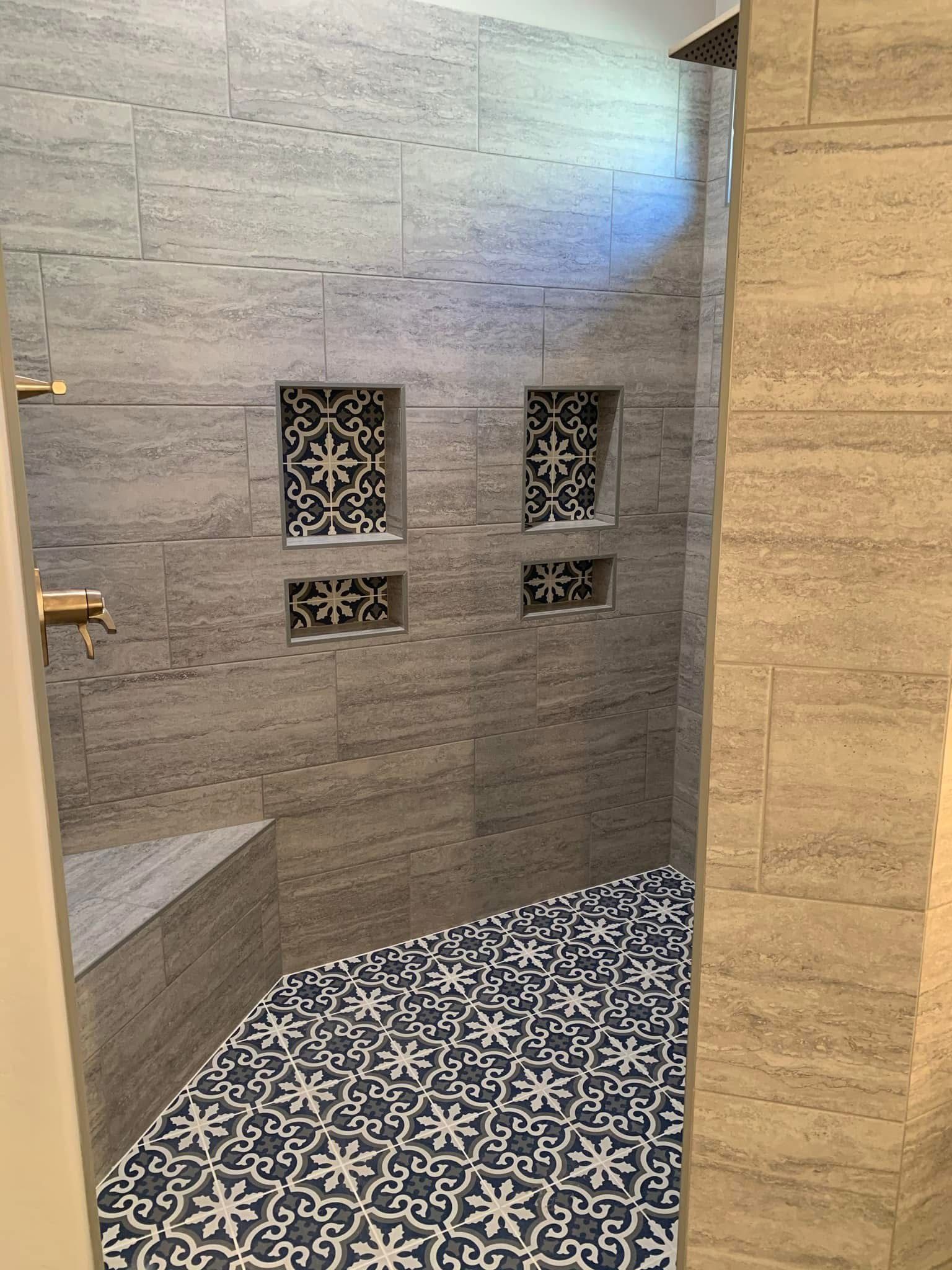 Modern shower with gray tile walls and black-and-white patterned floor accents.